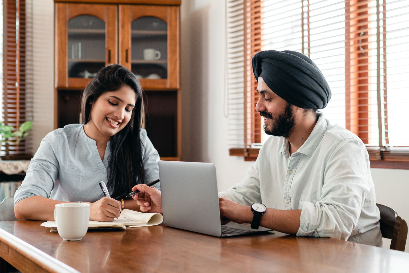 Two Indian professionals collaborating around a laptop in an office
